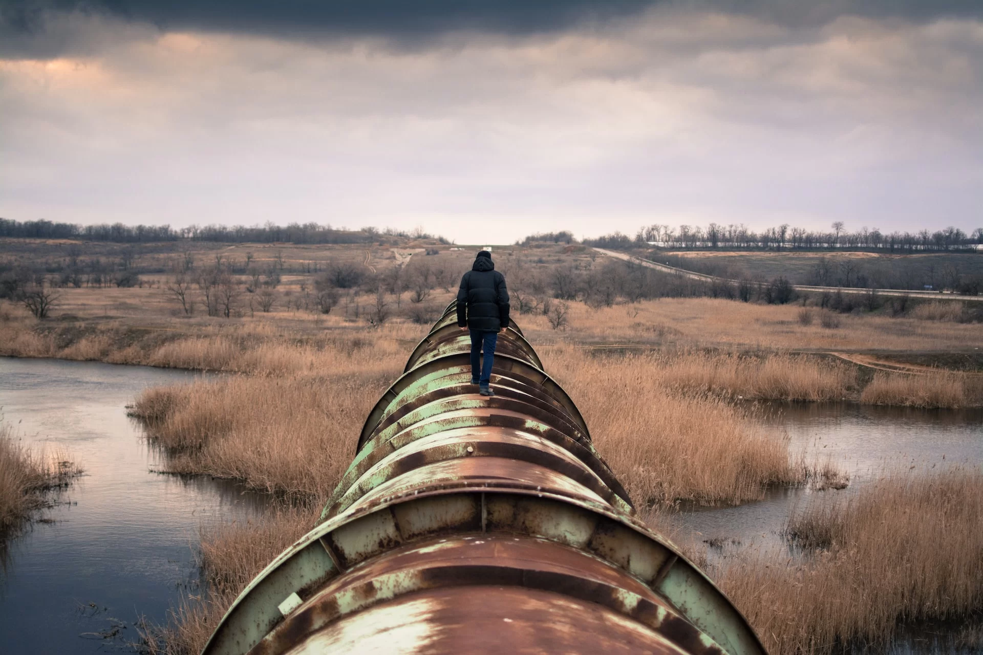 Homem de costas caminhando sobre um cano, representando o pipeline de liderança.